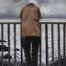 Painting of a back view of a lonely old man with arms resting on a handrail